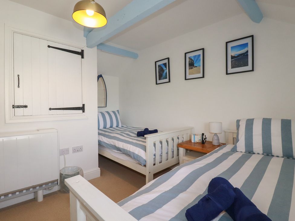 A bedroom with two beds and a bedside table at Puffin Cottage in Tintagel