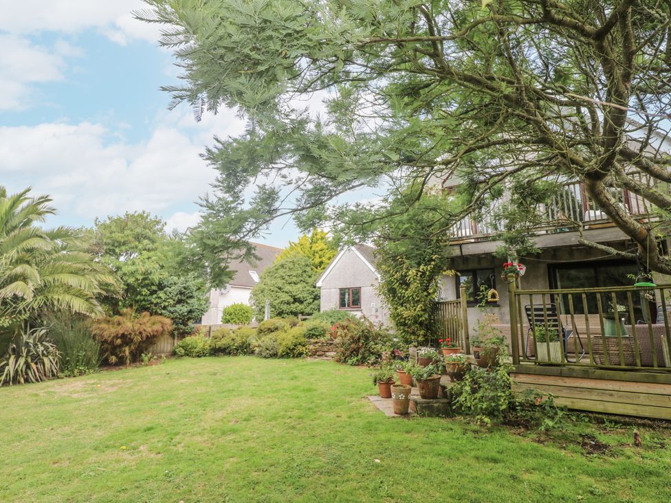 A garden with grass, trees, and a house in the background at 6 The Links Praa Sands