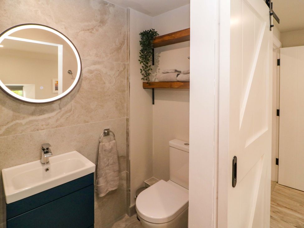 A bathroom with a sink, toilet, and shelves at Valley View House in Kealkill, County Cork