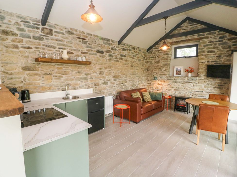 A living room with a kitchen area and sofa at The Stall near Kealkill, County Cork