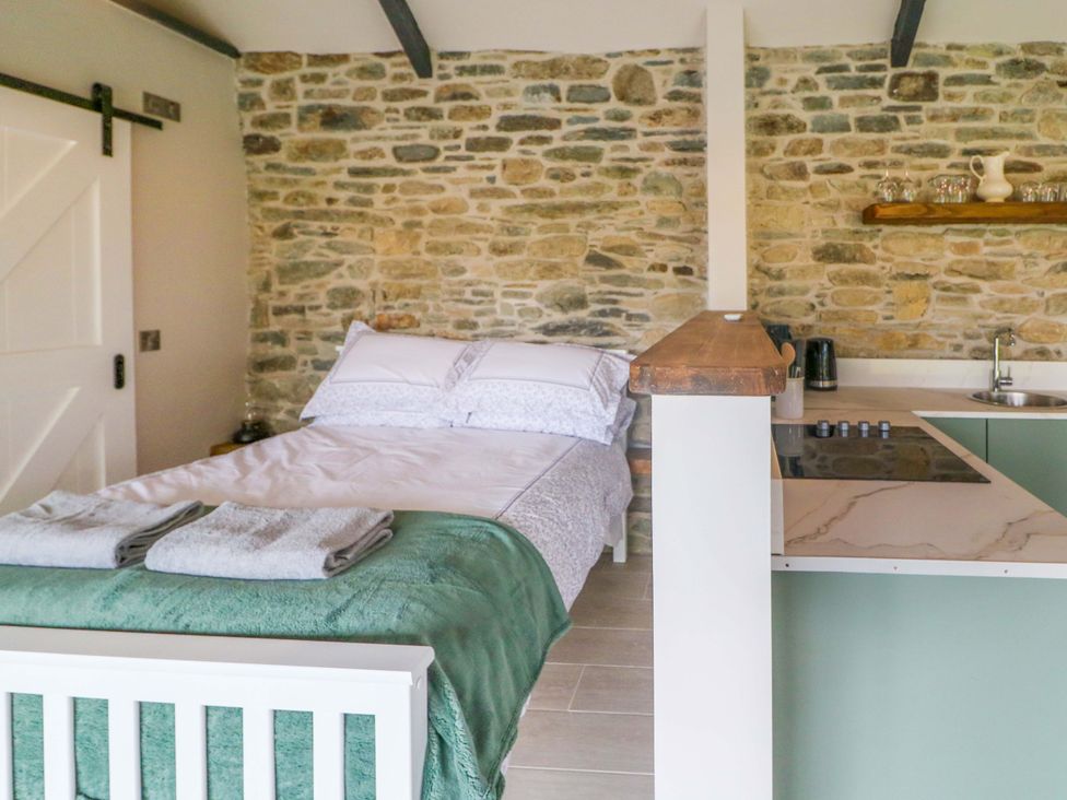 A bedroom with a bed and kitchen area at The Stall near Kealkill, County Cork
