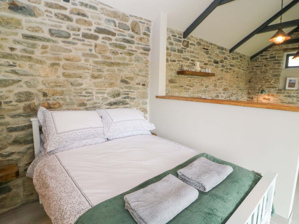 A bedroom with a bed and stone wall at The Stall near Kealkill, County Cork