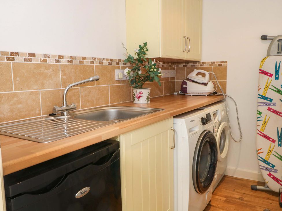 A laundry room with a sink, washing machine, and ironing board at The Warren in Chester