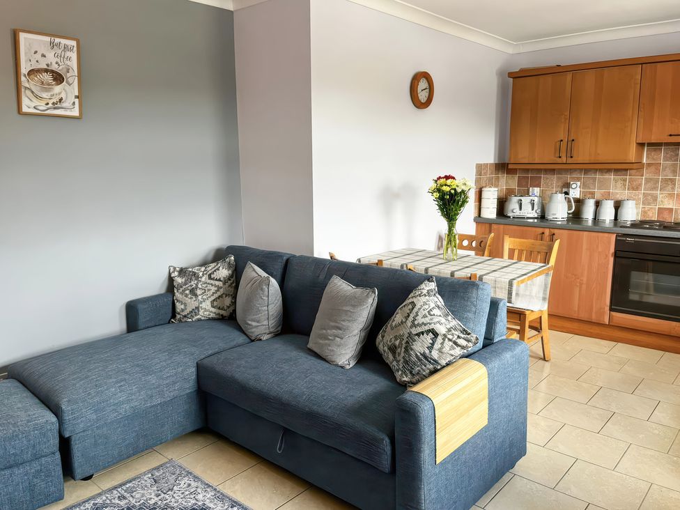 A living room with a sofa and dining area at Shalom Apartment 98B in Markethill