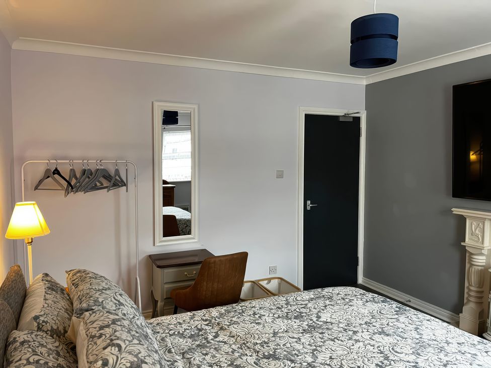 A bedroom with a bed, lamp, and a mirror at Shalom Apartment 98B in Markethill