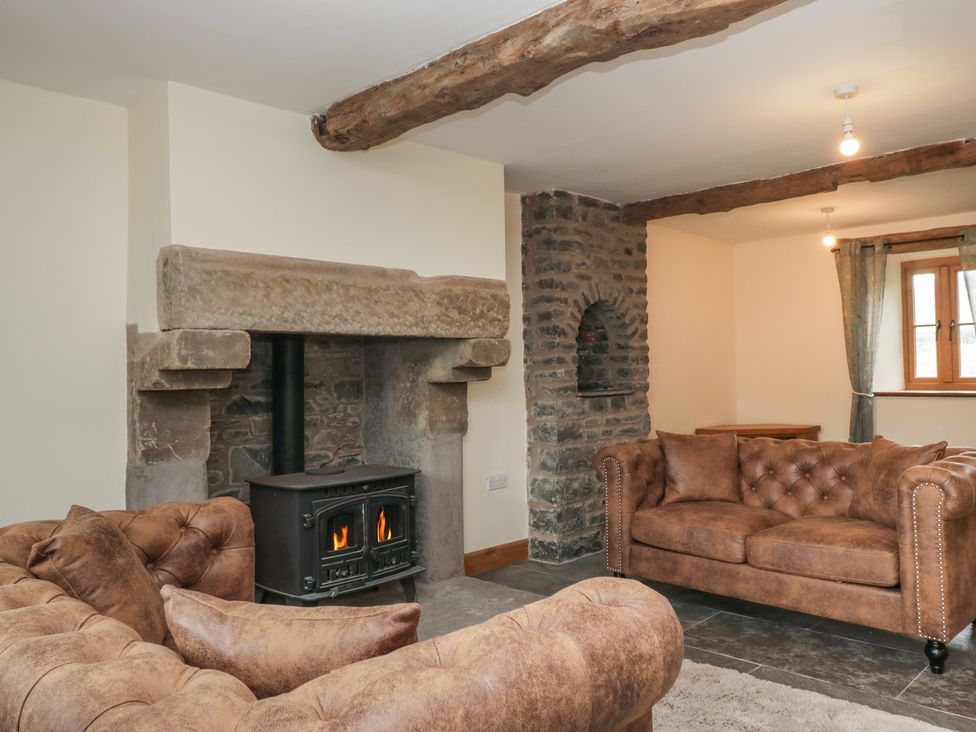 A living room with a fireplace and sofas at Howgill Head in Kendal