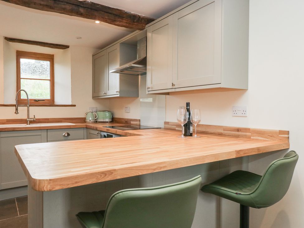 A kitchen with cabinets and a bar counter at Howgill Head in Kendal