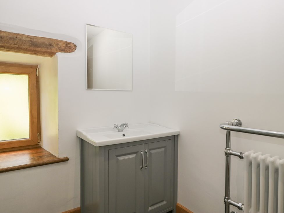 A bathroom with a sink, mirror, and radiator at Howgill Head in Kendal