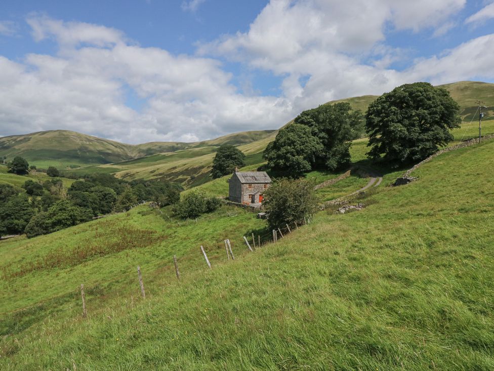 A cottage surrounded by trees and hills at Howgill Head in Kendal