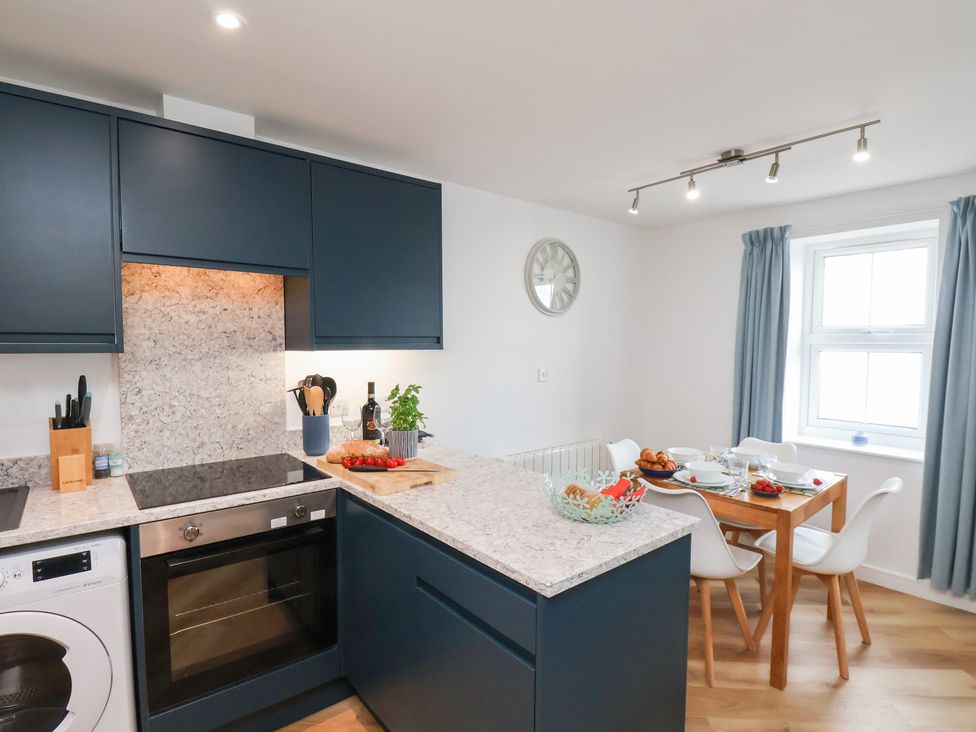 A kitchen with a stove, washing machine, table, and chairs at Belle's View in Scarborough