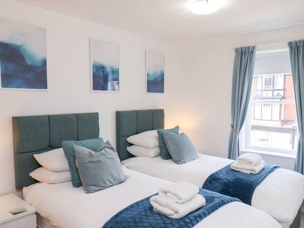 A bedroom with twin beds and pictures on the wall at Belle's View in Scarborough