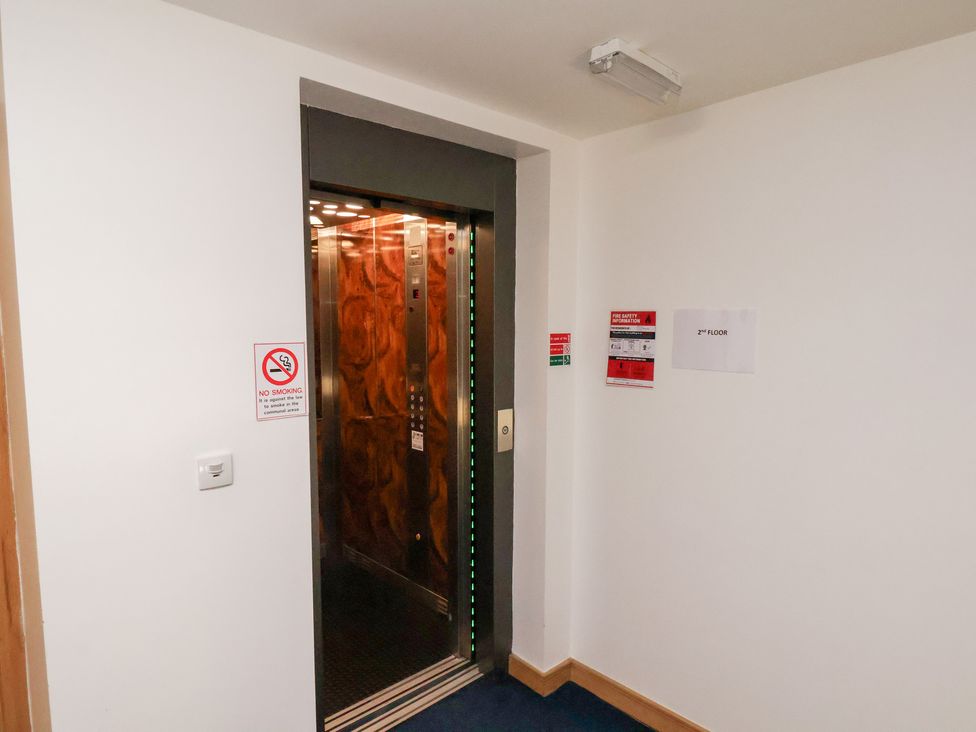 A corridor with an elevator and signs at Belle's View Scarborough