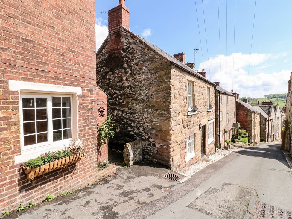 A narrow street with stone and brick houses and a flower box on a window at The Beehive in Wirksworth
