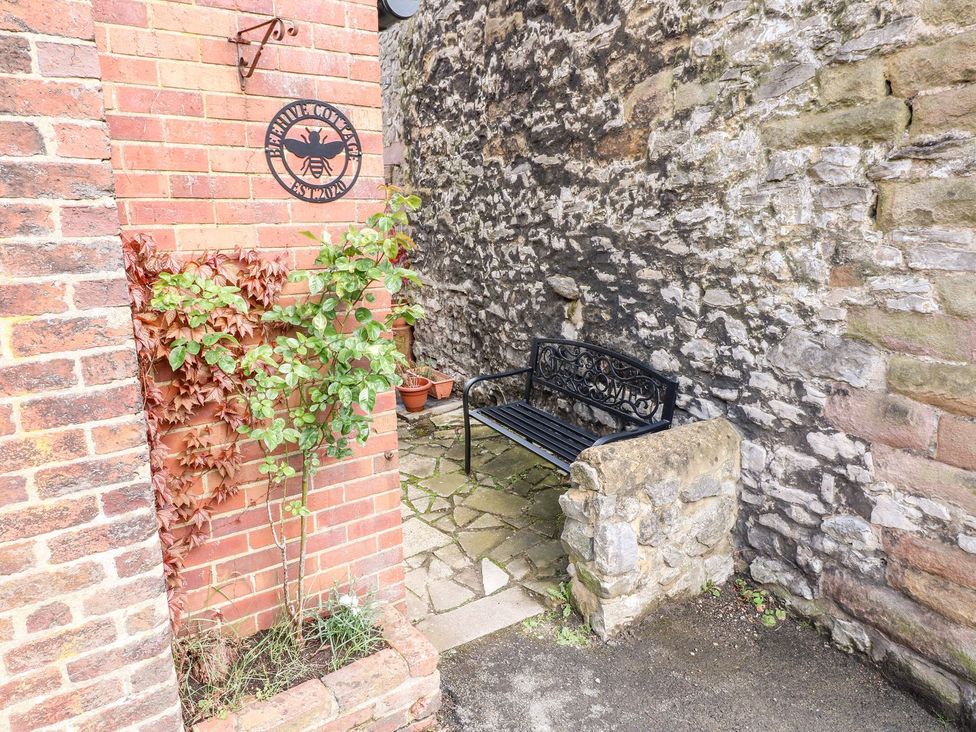 A small outdoor seating area with a metal bench surrounded by brick and stone walls at The Beehive in Wirksworth