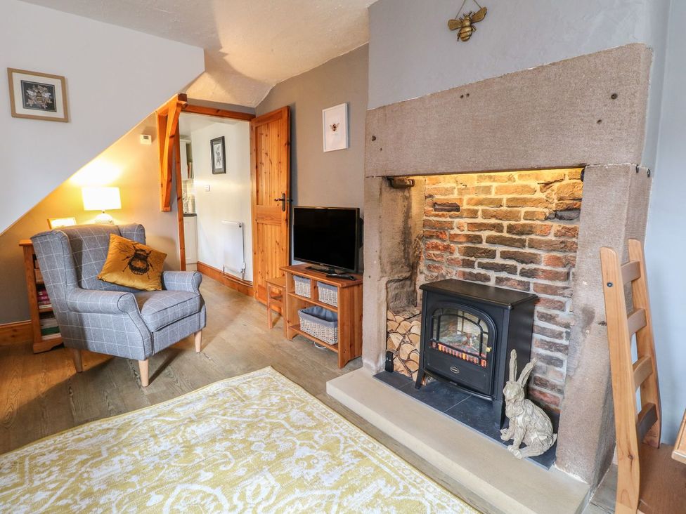 A living room with a fireplace armchair and television at The Beehive in Wirksworth