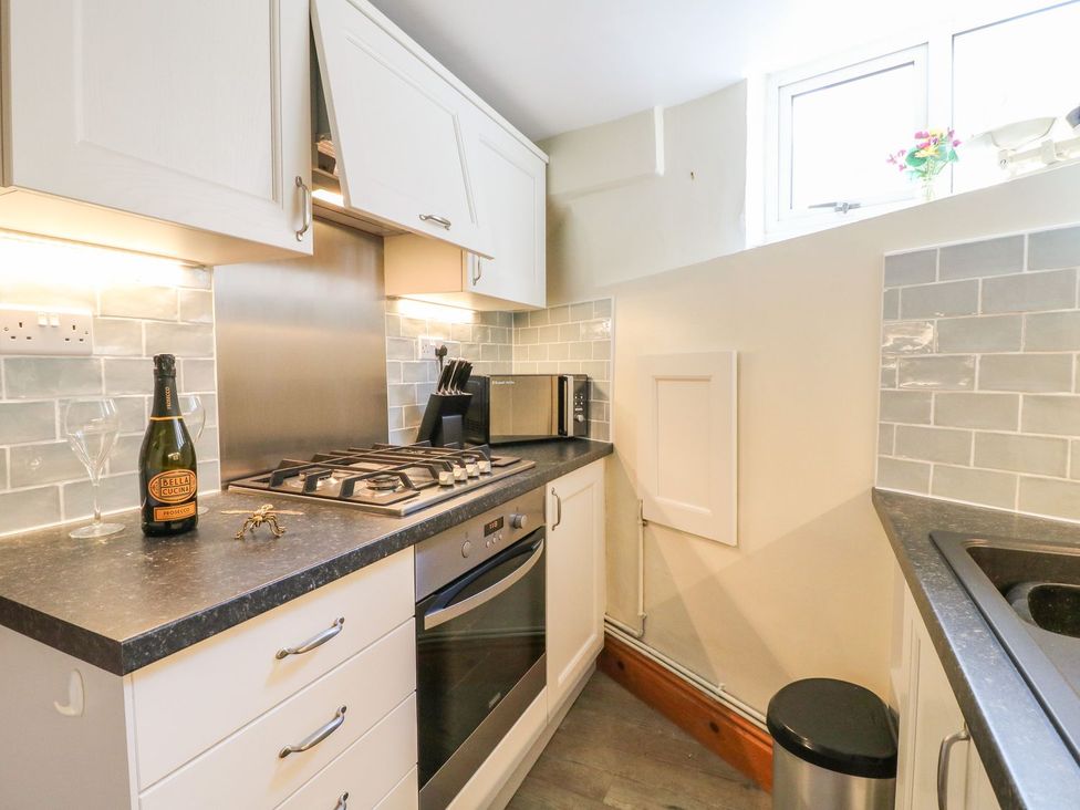 A compact kitchen with a stove oven microwave utensils and a bottle on the counter at The Beehive in Wirksworth
