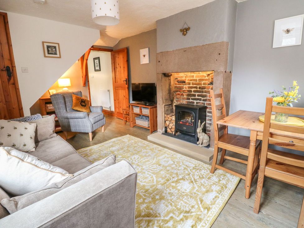 A living room with a sofa armchair fireplace and dining table at The Beehive in Wirksworth