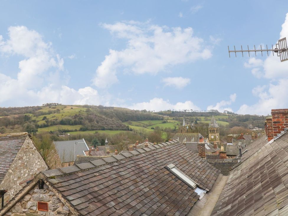 Roofs of stone buildings with antennas and hills in the background at The Beehive in Wirksworth