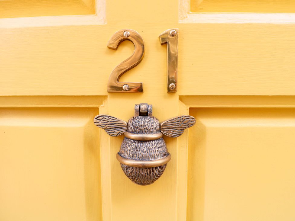 A door with a bee knocker and house number 21 at The Beehive in Wirksworth