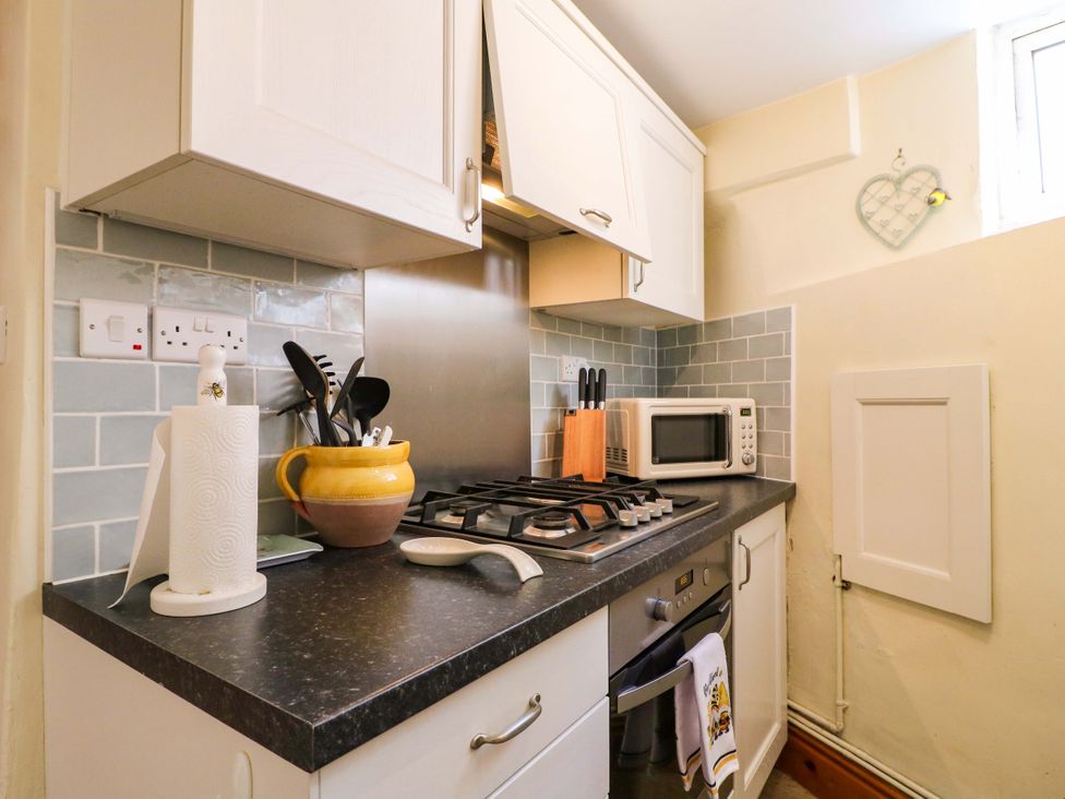 A kitchen with a gas stove and microwave at The Beehive in Wirksworth