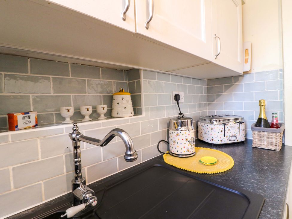 A kitchen with a sink and various containers at The Beehive in Wirksworth