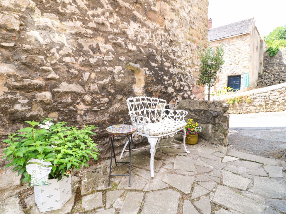 A seating area with a bench and table near a stone wall at The Beehive in Wirksworth