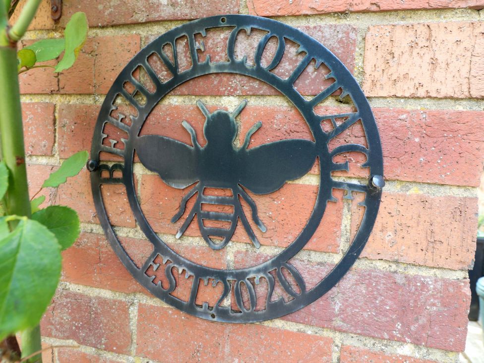A sign with a bee symbol on a brick wall at The Beehive in Wirksworth