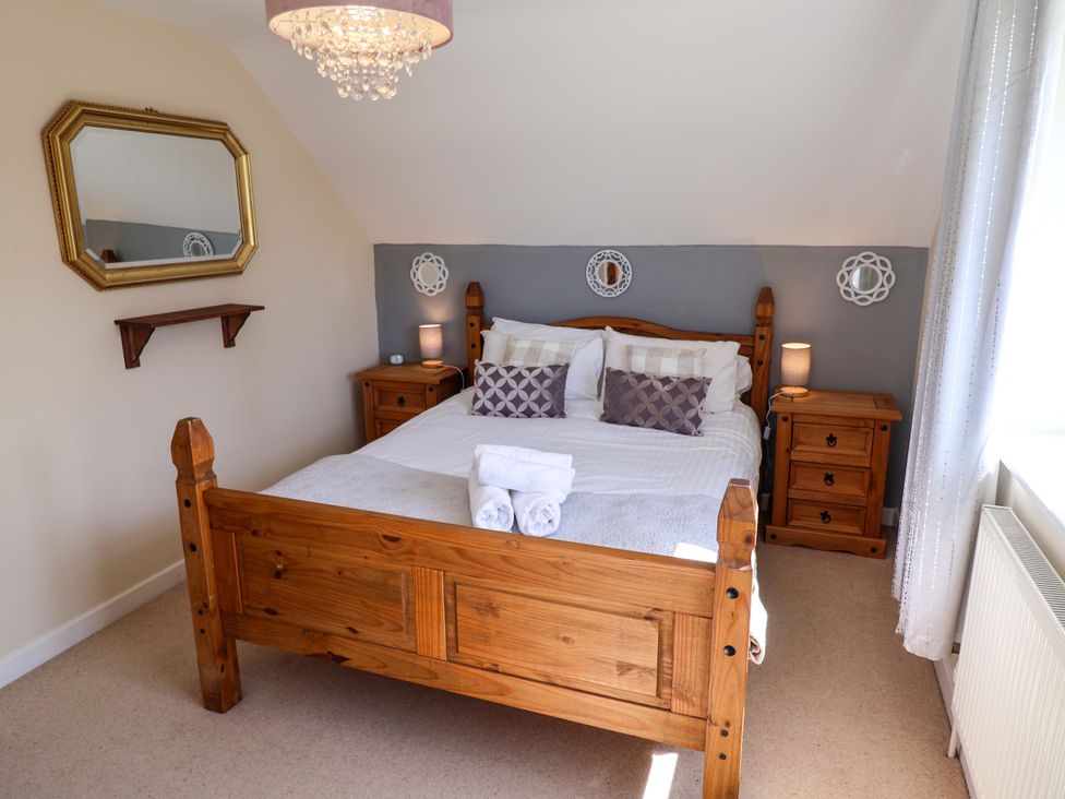 A bedroom with a wooden bed and bedside tables at Rosemarie Annexe in Axminster