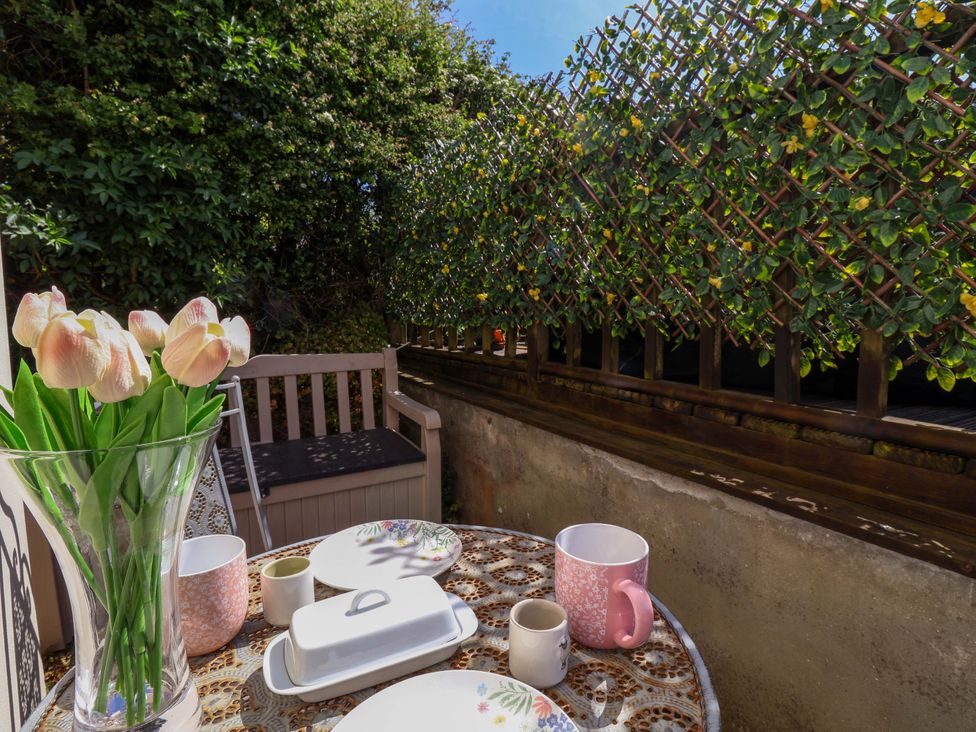 A table with tulips and mugs on a patio at Rosemarie Annexe in Axminster