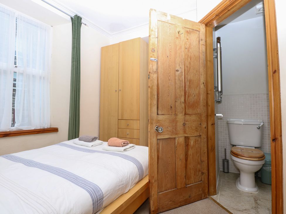 A bedroom with a bed and a toilet visible in Captain’s Quarters in Porthmadog