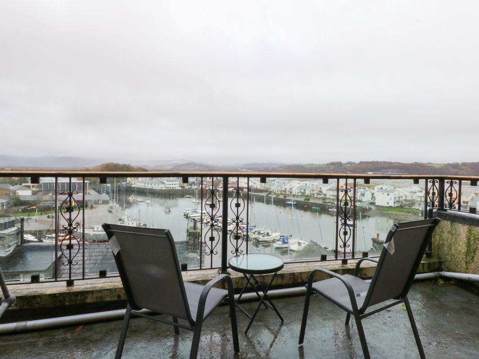 A balcony with chairs and a table overlooking a marina at Captain’s Quarters in Porthmadog