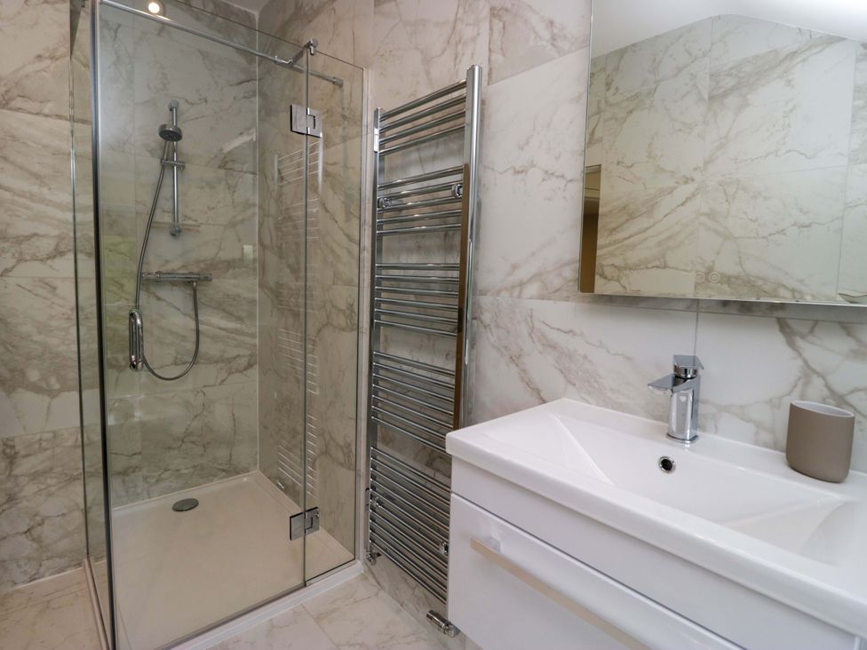A bathroom with a shower, sink and towel rail at Dove Cottage in Ambleside