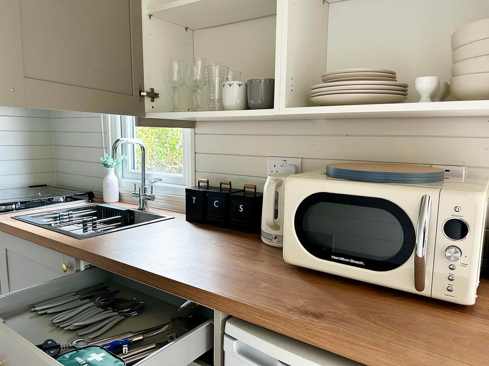 A kitchen with microwave, sink, and gas stove at Buzzards Lodge near Victoria