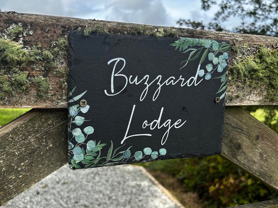 A sign for Buzzard Lodge attached to a wooden fence