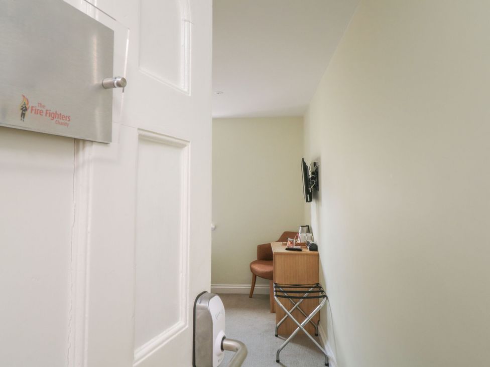 A room with a chair and table and a television at The Devon Drift in Chudleigh