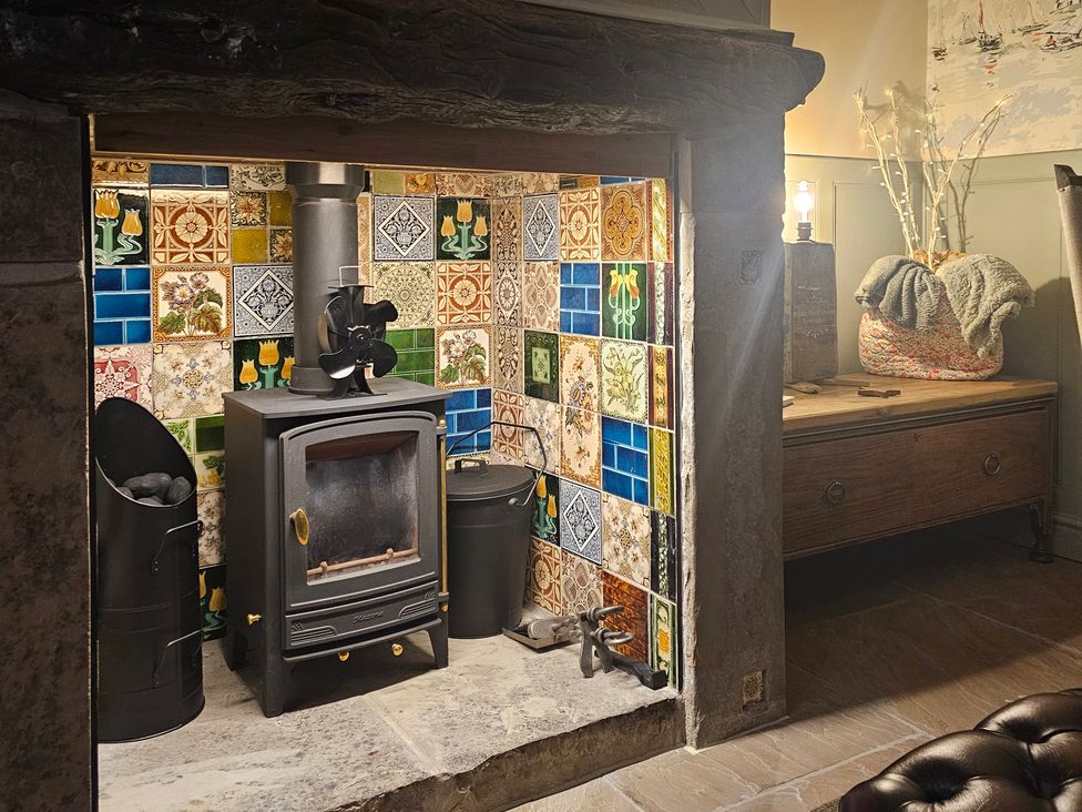 A living room with a wood stove and decorative tiles at Driftwood in Bridlington