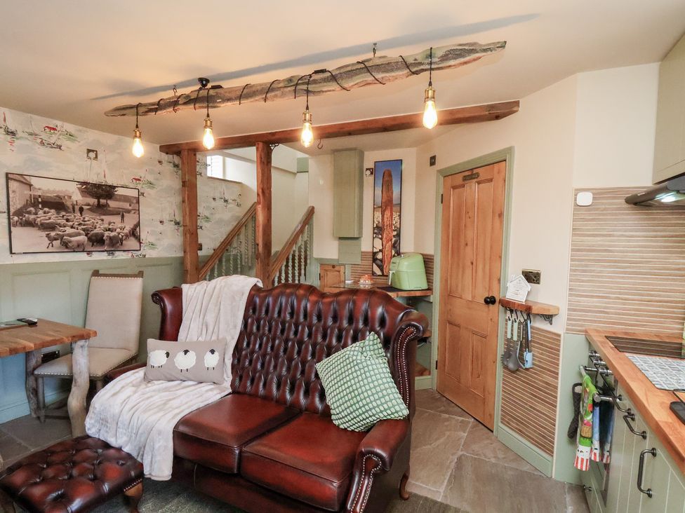A living room with a leather sofa and wooden table at Driftwood in Flamborough