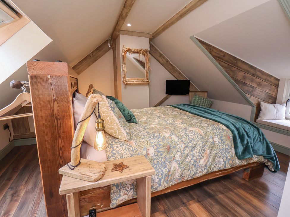 A bedroom with a wooden bed and a television at Driftwood in Flamborough