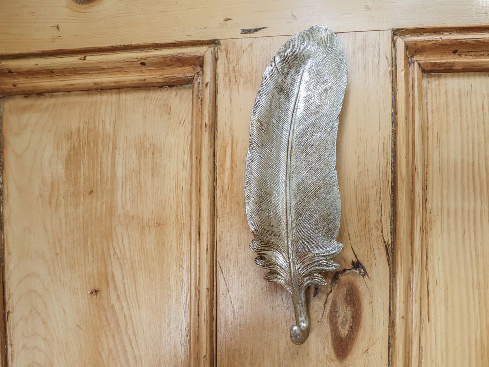 A decorative feather hook on a wooden door at Driftwood Flamborough