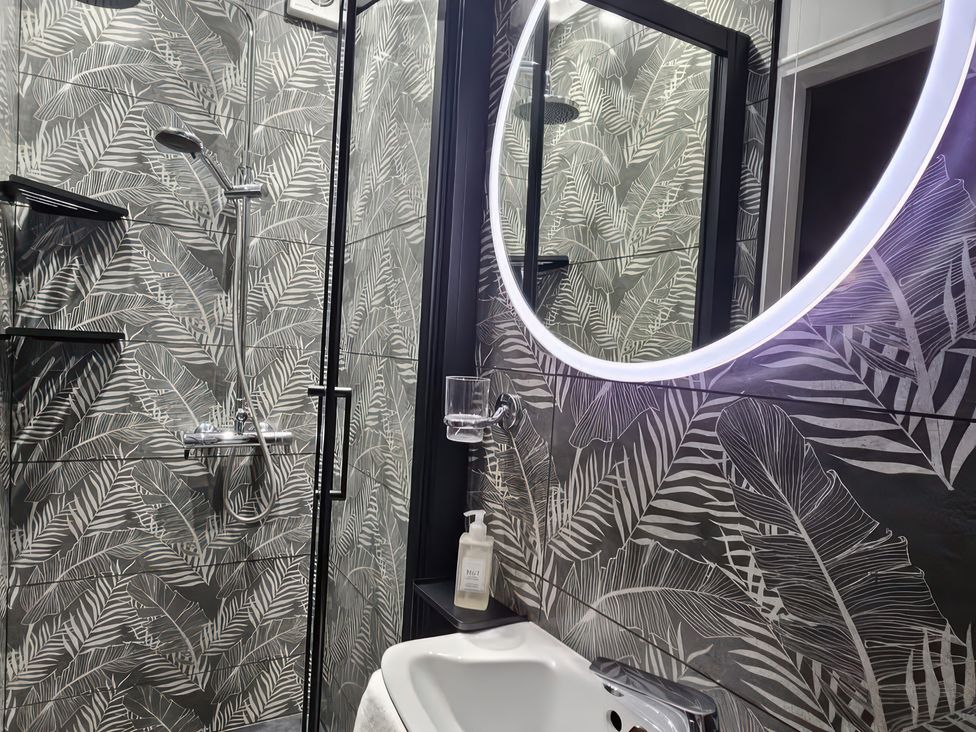 A bathroom with a shower and round mirror at Seaglass in Flamborough