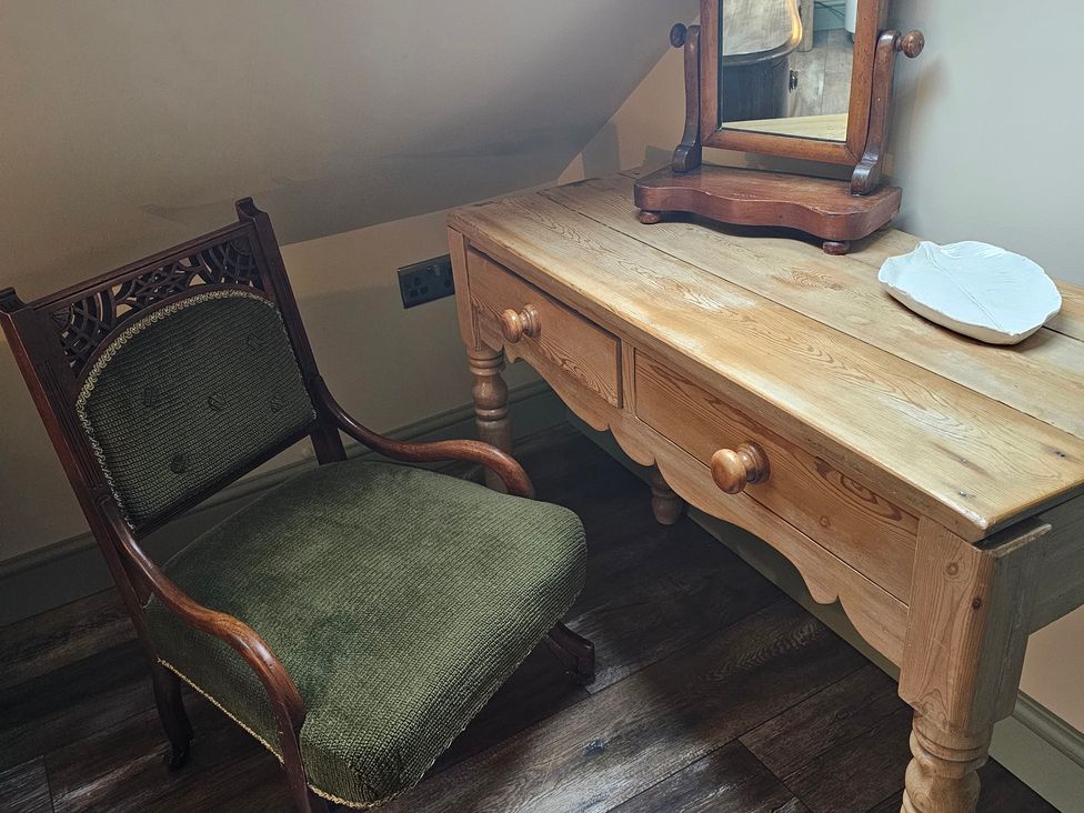 A chair and desk with a mirror and a shell object at Seaglass in Flamborough