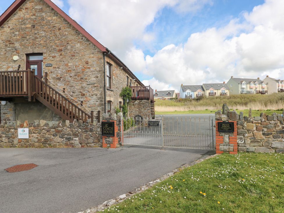 A stone building with a gate and staircase at The Coach House in Broad Haven