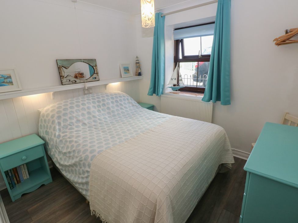 A bedroom with a bed and nightstand at Puffin Nook in Broad Haven