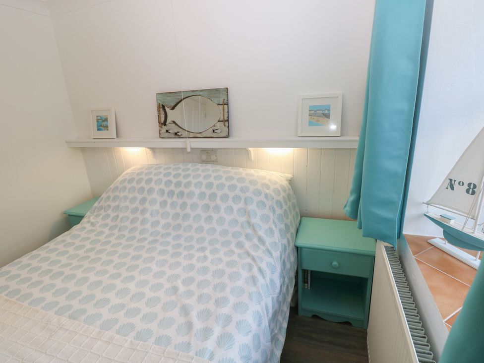 A bedroom with a bed and bedside table at Puffin Nook in Broad Haven