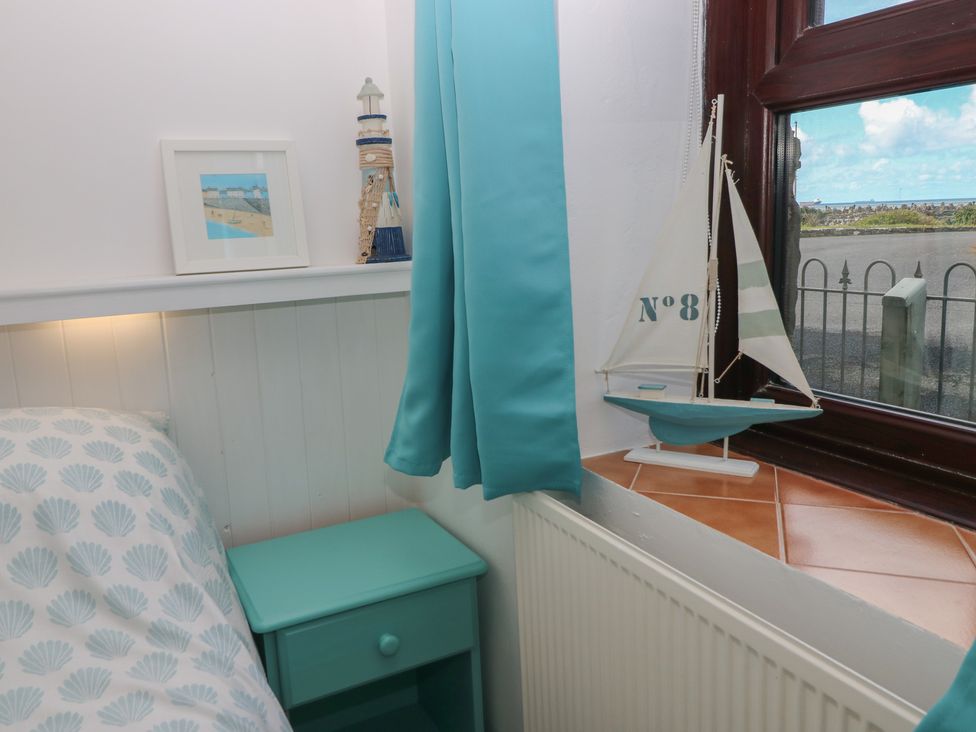 A bedroom with a bed and bedside table at Puffin Nook in Broad Haven