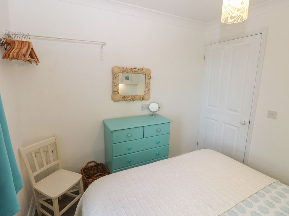A bedroom with a bed and a drawer unit at Puffin Nook in Broad Haven