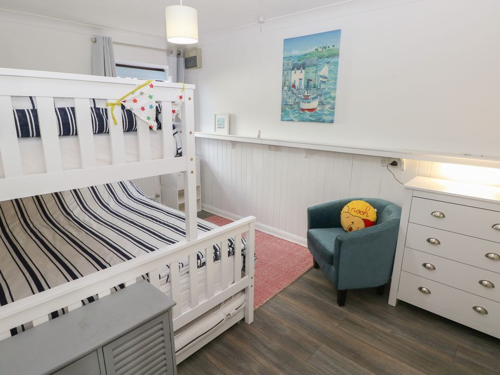 A bedroom with a bunk bed and armchair at Puffin Nook in Broad Haven