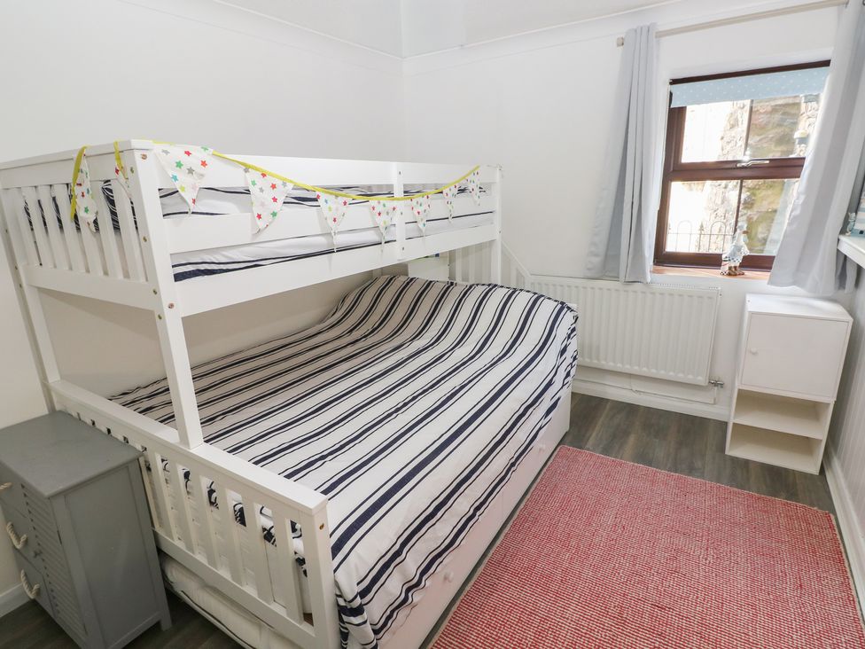 A bedroom with a bunk bed and striped bedding at Puffin Nook in Broad Haven
