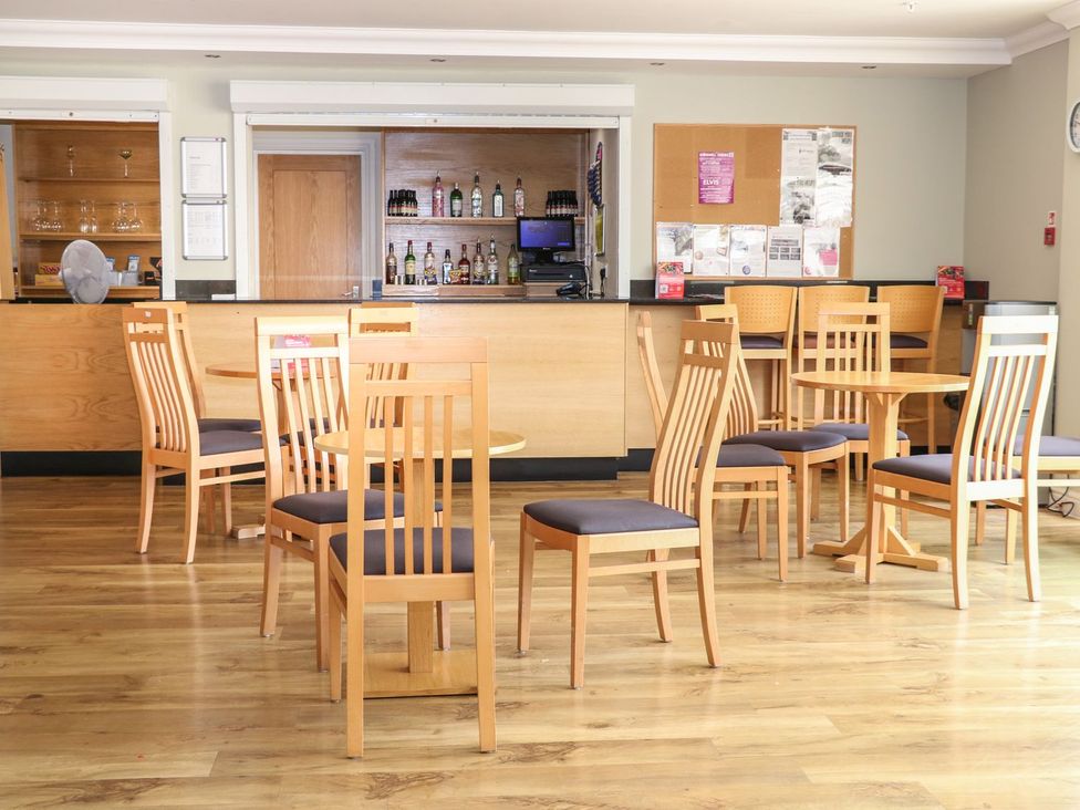 A bar area with wooden chairs and tables at Pebble Path in Littlehampton
