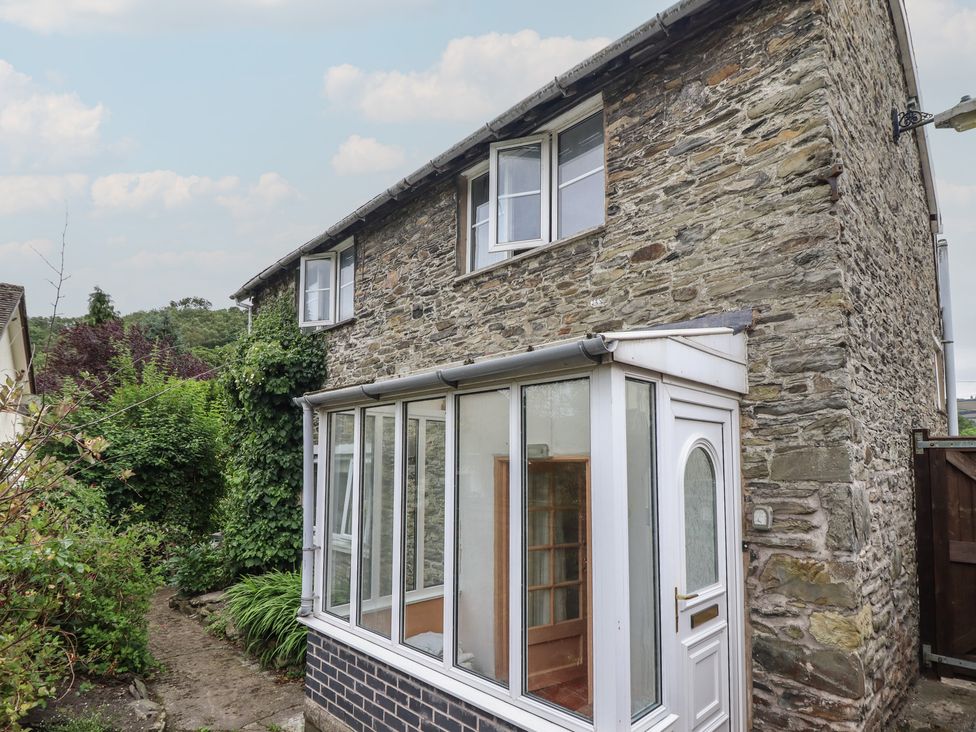 A stone house with a glass conservatory and garden path at Hafod in Llangollen
